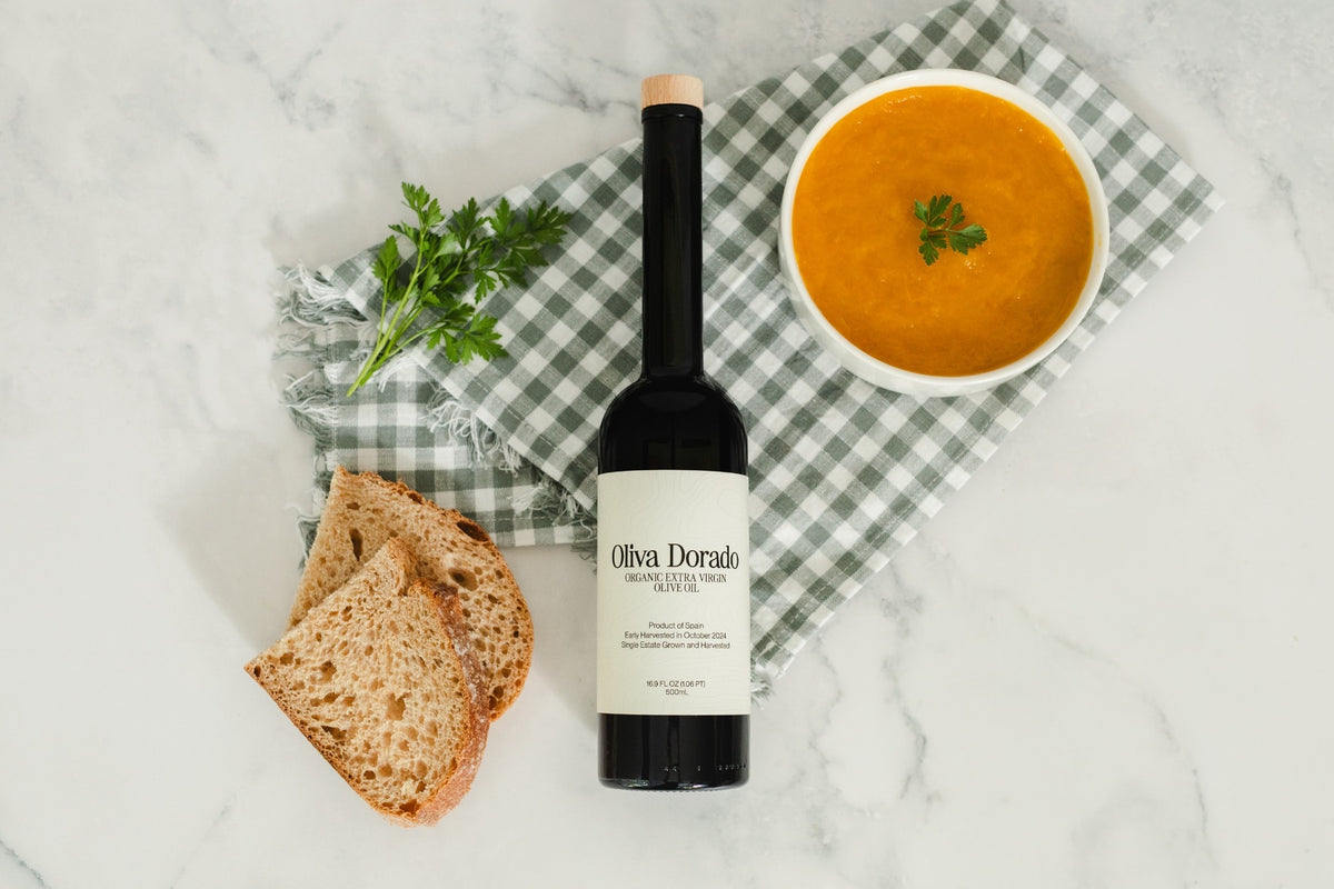 A bottle of Oliva Dorado olive oil with warm bread and soup